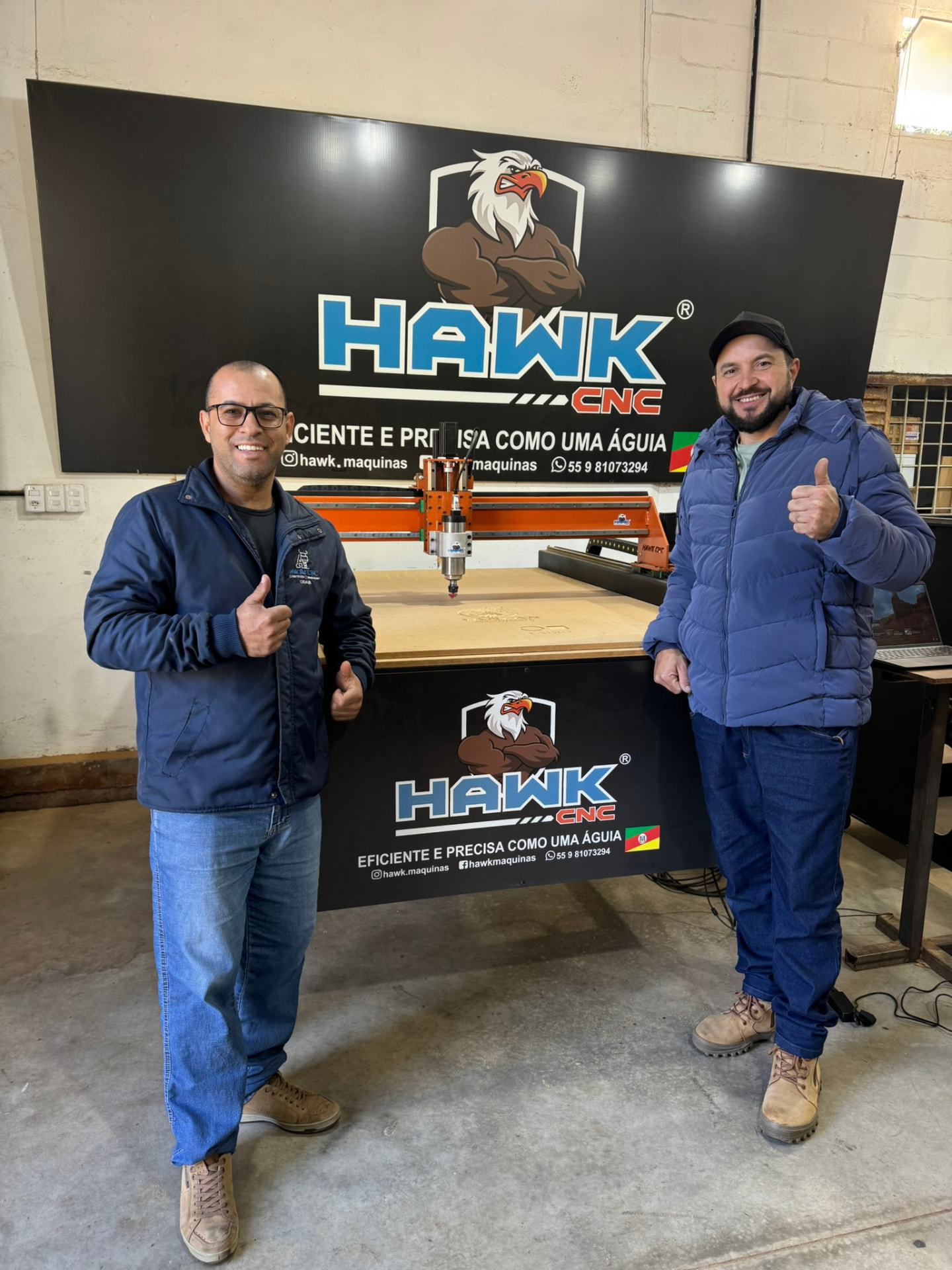 Dois clientes ao lado da Router CNC Hawk na oficina